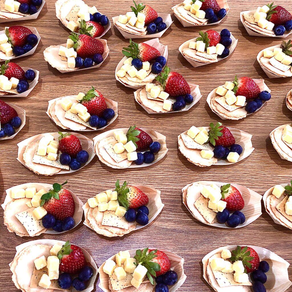 Mini fruit and cheese platters with strawberries, blueberries, and cheese cubes for catering.